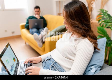 Woman working on laptop with man in background Stock Photo