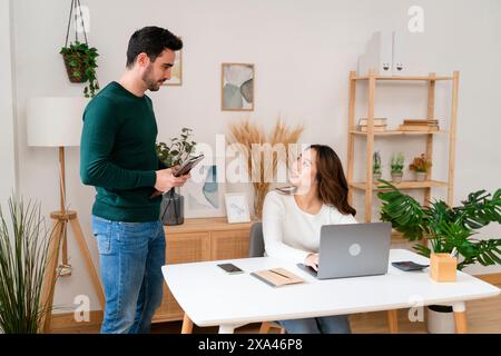 Man and woman discussing in a modern office setting Stock Photo