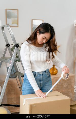 Woman measuring a cardboard box with a tape Stock Photo