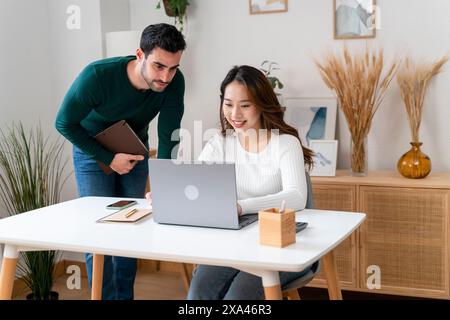 Two colleagues working on a laptop in a modern office. Stock Photo