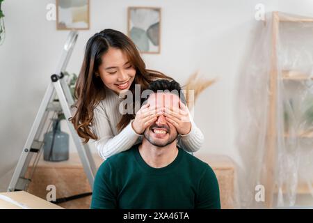 Woman covering man's eyes with her hands in a playful moment Stock Photo