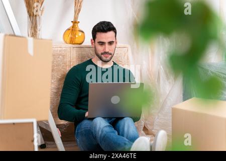 Man with laptop among moving boxes Stock Photo