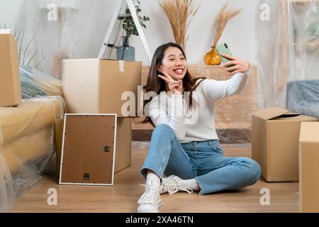 Woman taking a selfie amidst moving boxes. Stock Photo