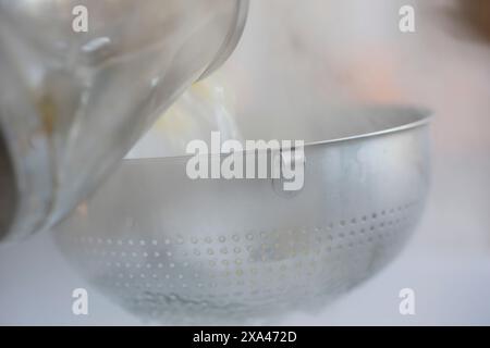 Pouring boiling water and pasta into a colander Stock Photo