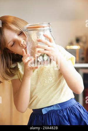 Young Girl Inspecting Jar of Coins Stock Photo