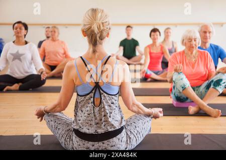Back View of Yoga Instructor Teaching Yoga Class Stock Photo