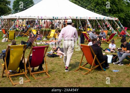 Rear, back view man straw hat walking to marquee in Hay Festival book shop garden people reading 2024 Hay-on-Wye Wales UK Great Britain  KATHY DEWITT Stock Photo