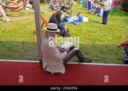 Older man wearing straw hat sitting in the shade on a sunny day in book shop garden Hay Festival 2024 Hay-on-Wye Wales UK Great Britain   KATHY DEWITT Stock Photo