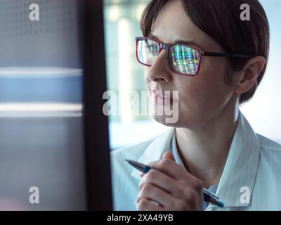 Genomics, Scientist viewing human DNA profiles on screen during testing in the lab Stock Photo
