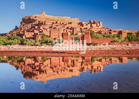 Ait-Benhaddou, Morocco. Famous example of clay architecture, ksar kasbah in North Africa, Atlas Mountains. Sunrise water reflection. Stock Photo