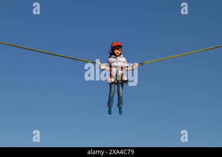 A little girl on a bungee jump trampoline  during an event at the Red Brick Warehouse (Aka Renga soko) in Sakuragicho, Yokohama, Kanagawa, Japan. Stock Photo