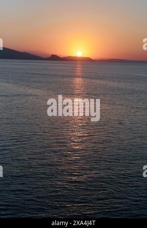 The sun is casting a warm orange glow as it dips below the horizon ...