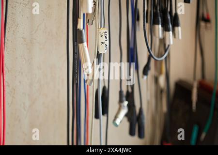 A selection of neatly organized audio cables hangs against a wall, each cable labeled for easy identification. Stock Photo