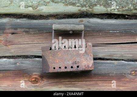 Rare iron working on coals.  Hanging on a nail hammered into the wall of an old wooden shed. Stock Photo
