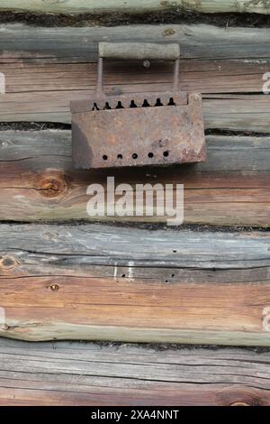 Rare iron working on coals.  Hanging on a nail hammered into the wall of an old wooden shed. Stock Photo