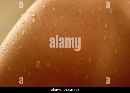 Close-up view of skin with water droplets, highlighting the texture and intricate detail of the human skin surface with a warm color tone. Stock Photo