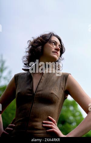 Confident woman in a sleeveless top posing outdoors with hands on hips Stock Photo