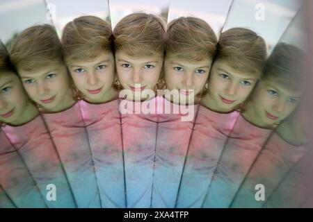 Multiple reflections of a young person's face in a kaleidoscopic pattern. Stock Photo