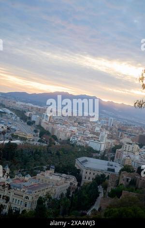 Sunset view over a sprawling city with buildings and distant mountains under a pastel-colored sky. Stock Photo