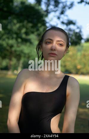 Woman with wet hair wearing a black sleeveless top standing outdoors. Stock Photo