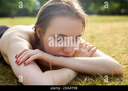 Woman relaxing on the grass with a thoughtful expression. Stock Photo