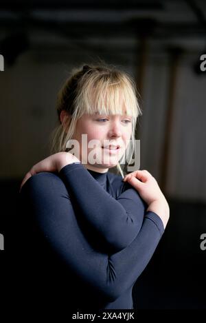 Woman stretching her arm before a workout in an indoor setting. Stock Photo