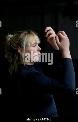 A focused young woman with a ponytail holding an apple and examining it intently. Stock Photo