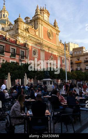 Seville, Spain. February 4, 2024 - A group of people sitting at cafe tables on Plaza del Salvador in front of Iglesia del Salvador Sevilla church. Stock Photo