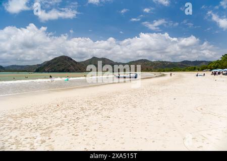 Holidaymakers and surfers on the golden tropical beach of Selong Belanak on the island of Lombok, Indonesia Stock Photo