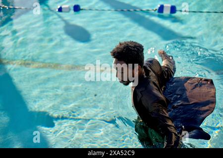 Man swimming in a pool with clothes on during a sunny day. Stock Photo