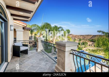 Scenic balcony view with pool, furniture, and fence Stock Photo