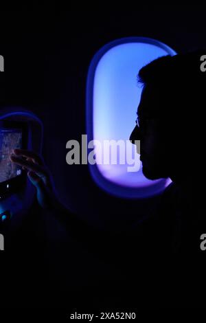 A person using a tablet near an airplane window at night Stock Photo