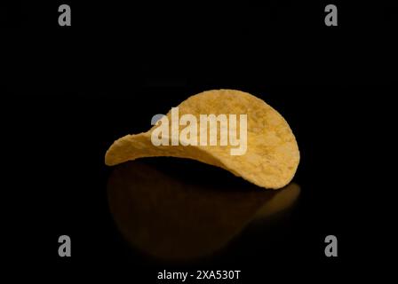 A close-up with a group (pile) of potato chips on a black background. Stock Photo