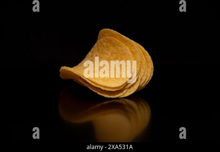 A close-up with a group (pile) of potato chips on a black background. Stock Photo
