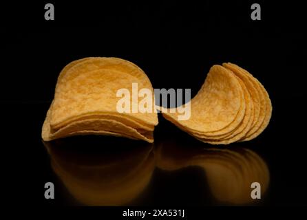 A close-up with a group (pile) of potato chips on a black background. Stock Photo