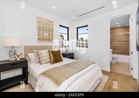 A large bed, white walls, and hardwood floors in a bedroom Stock Photo