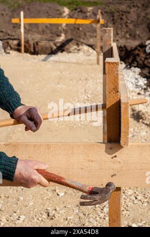 A man using a hammer for nailing on a construction site in southern Germany Stock Photo