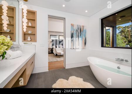 A white sink and bathtub next to a large mirror in a bathroom Stock Photo