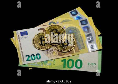 A close-up of Bitcoin coins on Euro bills against dark backdrop Stock Photo