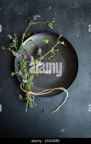 Rustic minimalistic summer table setting decorated with wild field flowers in dark colors Stock Photo