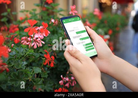 Woman texting via mobile phone outdoors, closeup. Device screen with messages Stock Photo