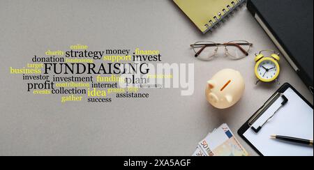 Workplace with different stuff on grey table, flat lay. Fundraising themed terms in word cloud. Banner design Stock Photo