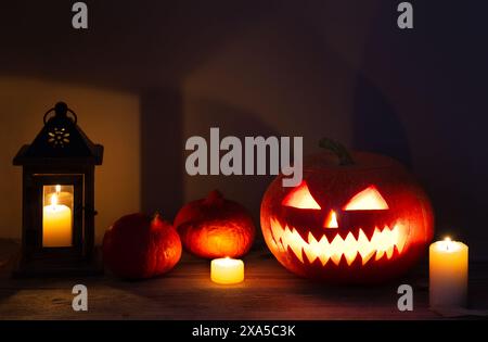 Halloween pumpkin head jack lantern with burning candles on old wooden table. Halloween design with pumpkins. Stock Photo
