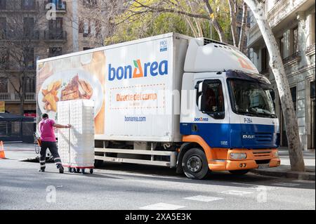 delivery truck of the food and meat company BonArea. The truck is parked in double rows and the delivery man pushes the cart with the products. Stock Photo