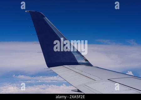 Airplane wing shown in flight over Southern California against clouds and blue sky. Stock Photo