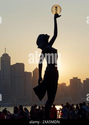 View of The Hong Kong Film Awards statue standing on the Hong Kong Avenue Of Stars on the Kowloon waterfront silhouetted against the setting sun Stock Photo