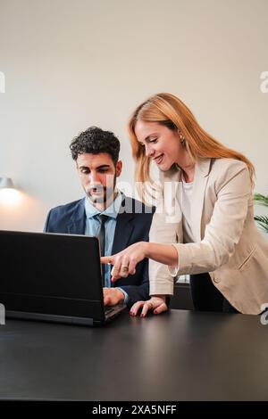 Vertical. One business woman and a businessman working together with a laptop on a job project. Two real coworkers planning using a computer. Teamwork of corporate employees on a brainstorming. High quality photo Stock Photo