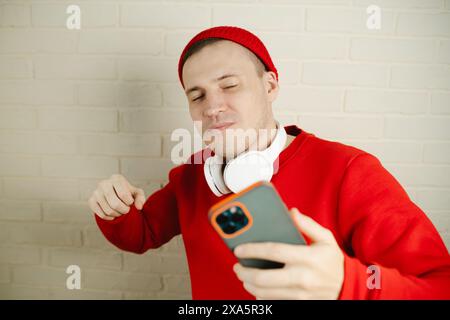 A man is wearing headphones and holding a cell phone in his hand. To be listening to music Stock Photo