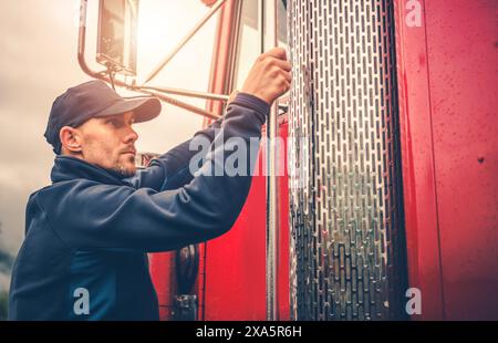 A Caucasian Commercial Truck Driver and His Red Semi Truck Stock Photo
