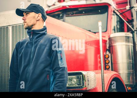 A Caucasian Semi Truck Driver in Front of His red truck Stock Photo
